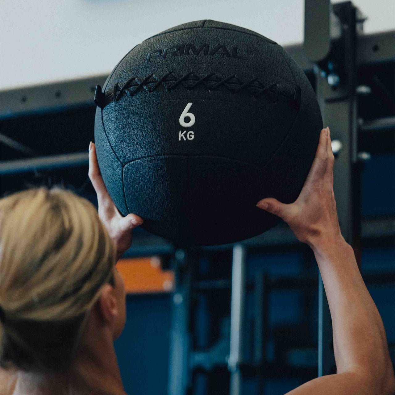 An athlete throwing a Primal branded wall ball in a gym setting.