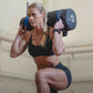 Woman performing a lunge movement with a sandbag in a gym.