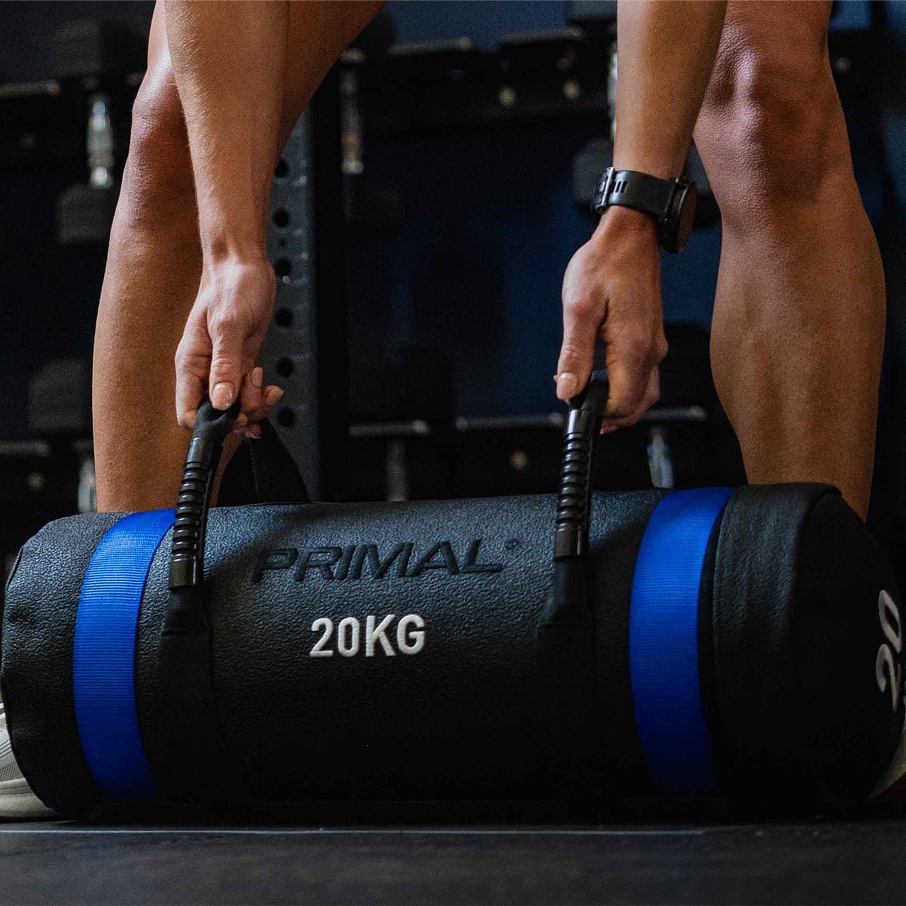 Person holding a 20kg Primal sand bag in a gym setting.