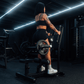 View from back of athlete using standing hip thrust machine with plates loaded onto bullhorns.