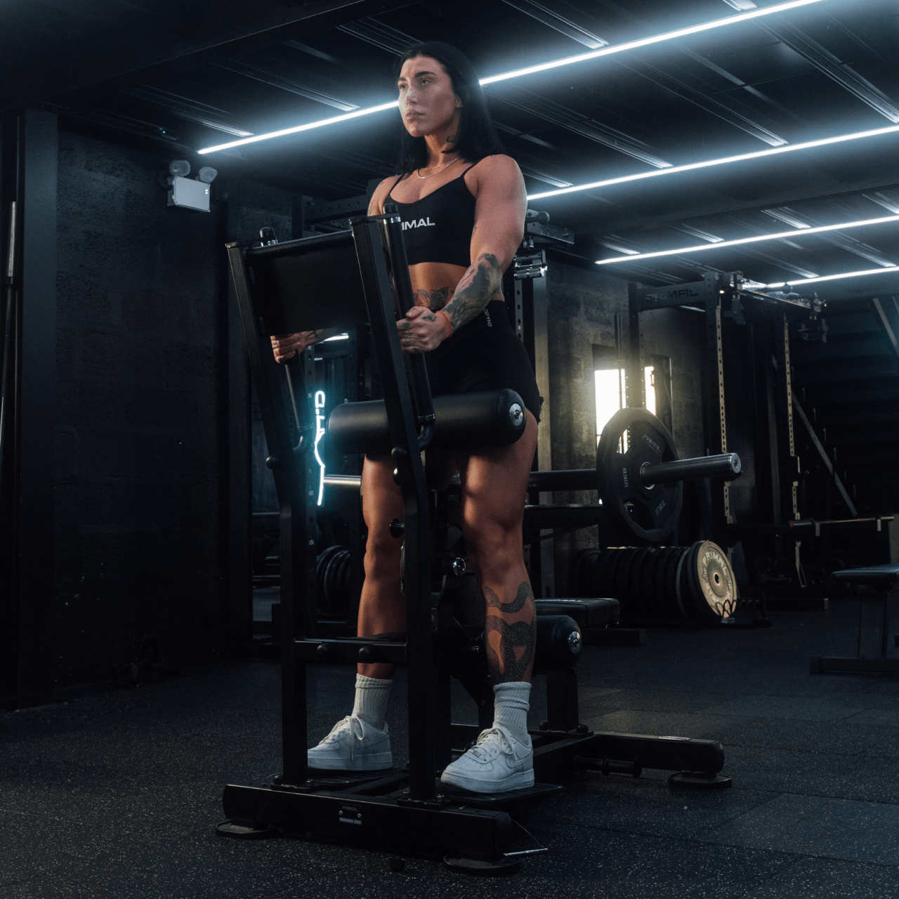 Athlete using plate-loaded standing hip thrust machine.