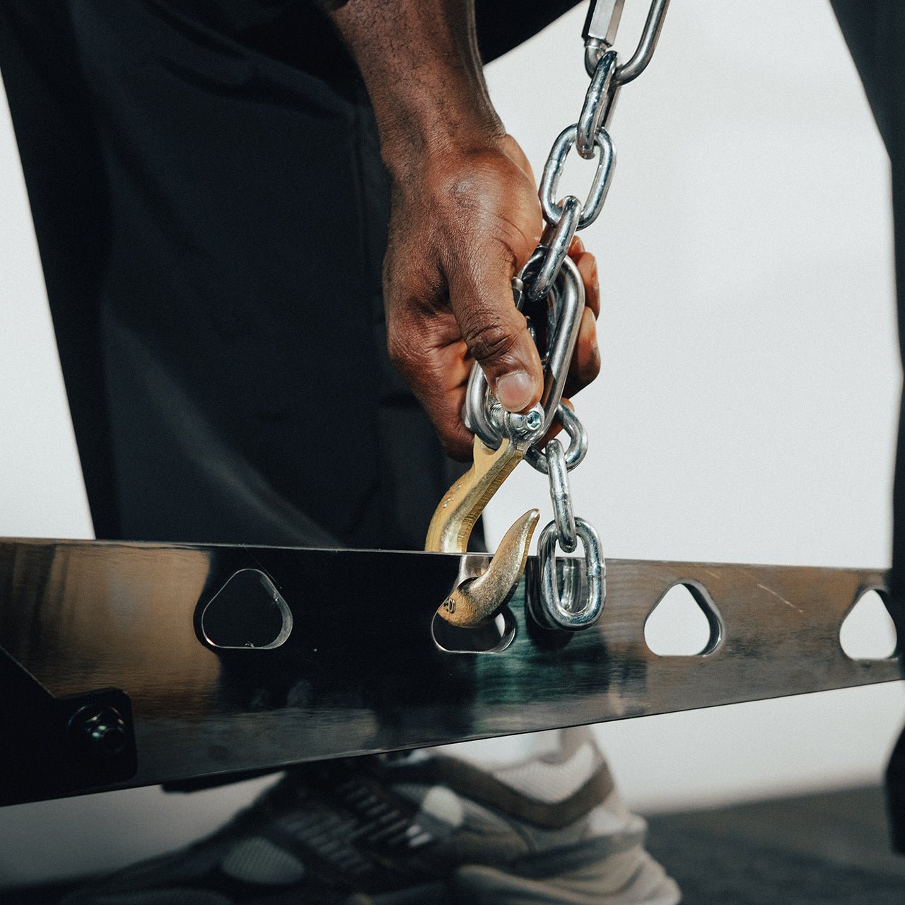 An athlete adjusting the height of a plate loaded belt squat machine.