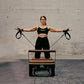 Woman exercising with Pilates reformer against a brick wall.