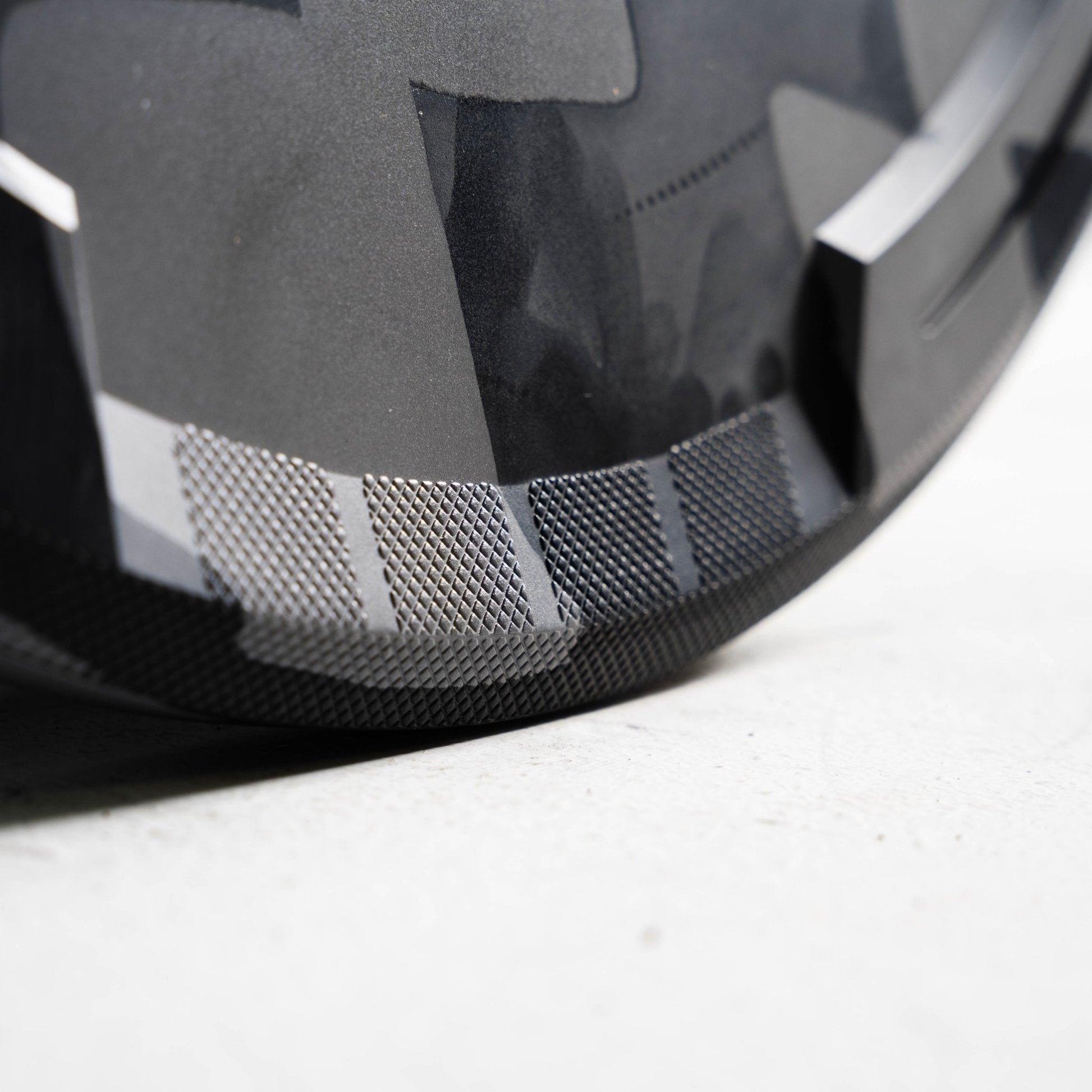 Close-up of a Grey & black bumper plate with a textured pattern on a light gray background
