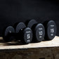 three single primal strength black urethane dumbbells on a wooden box